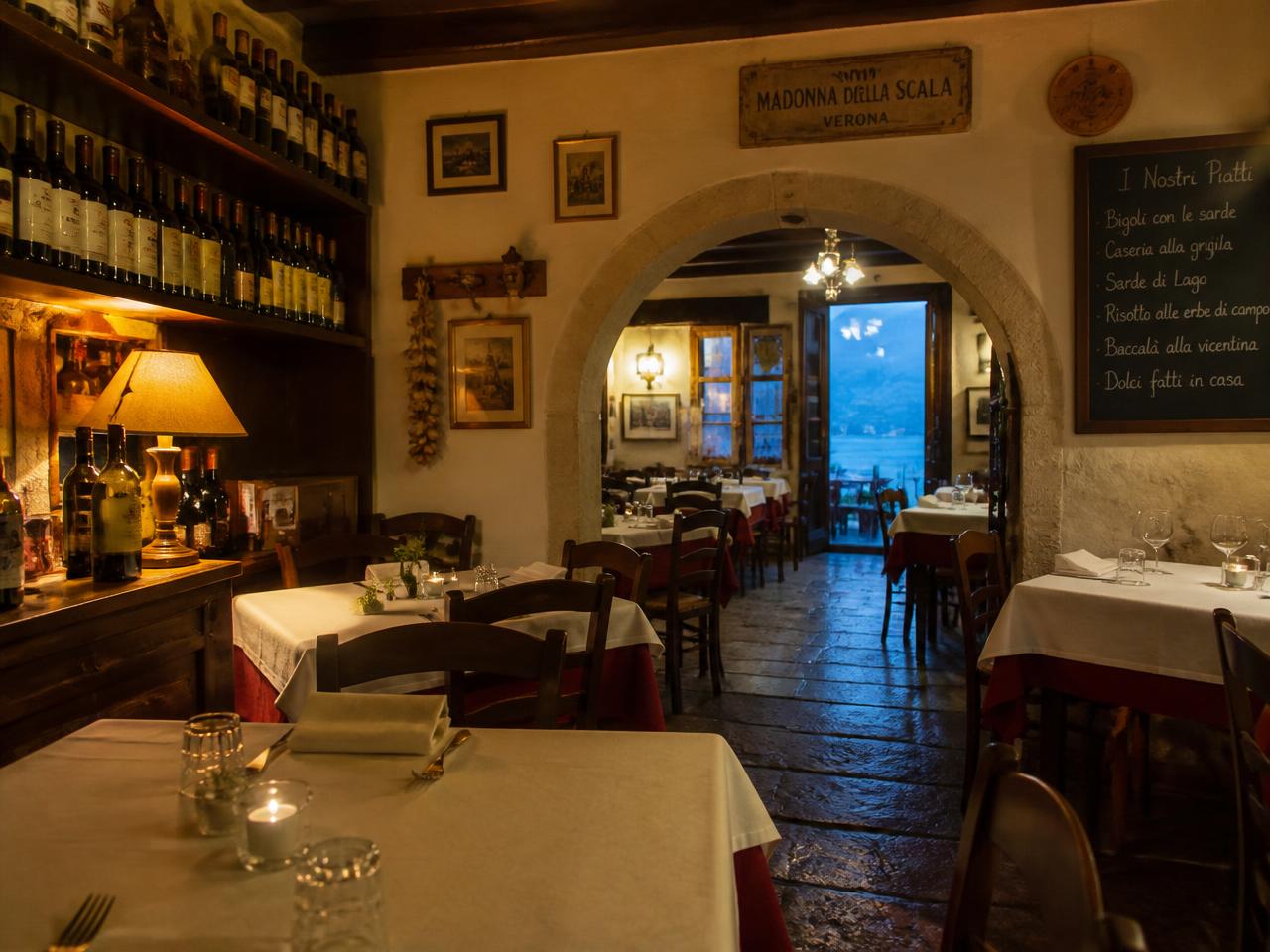 Sala interna della trattoria con tavoli apparecchiati, arco in pietra e bottiglie di vino